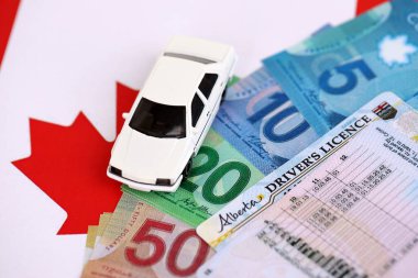 Canadian driving permit concept. Driver license and canadian dollars money bills on flag close up