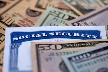 Social security number card on many US dollar money bills close up