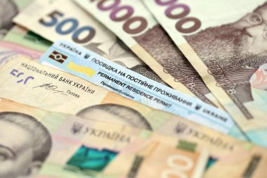 Ukrainian residence permit card or permanent resident card on Ukrainian money close up