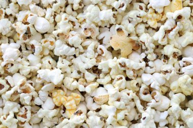 Büyük bir grup taze pişmiş patlamış mısır, sıcak sarı ışıkta yumuşak bir odak ile fotoğraflanmış, bir sokak gıda pazarında satışa sunuldu.