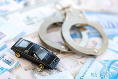 Birleşik Arap Emirlikleri kara para birimi faturaları ve kelepçeli oyuncak araba. Araba kazası kavramı.