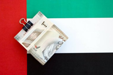 Birleşik Arap Emirlikleri kara para birimi banknotları bayrağa yakın duruyor. İş ve yatırım kavramı