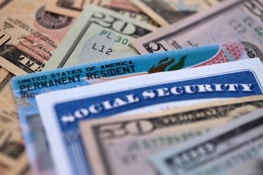 Social security number and permanent resident card with US dollar money bills close up