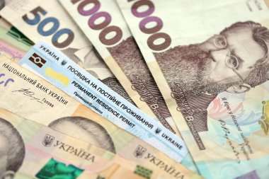 Ukrainian residence permit card or permanent resident card on Ukrainian money close up