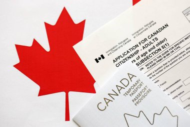 Canadian temporary passport and application for canadian citizenship lies on flag close up