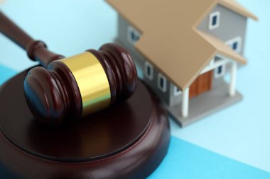 Generic toy house and judgement mallet on blue background close up