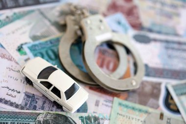 Mısır para birimi banknotları ve kelepçeli oyuncak araba. Araba kazası kavramı.