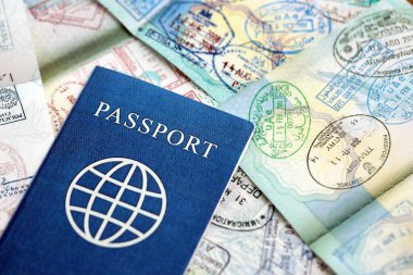 Birçok açık pasaport sayfası, bir sürü vize ve çeşitli ülkelerden pasaport kontrolünden giriş damgalarıyla dolu. Dünya çapında seyahat ve turizm kavramı