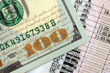 Amerikan ehliyetine 100 dolarlık banknot. Sürüş dersleri veya otomobil vergisi ödeme kavramı