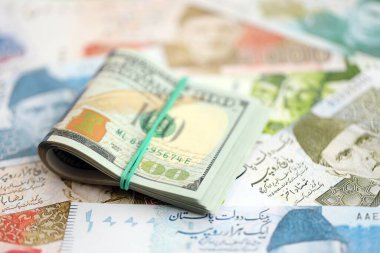 Bir sürü Amerikan doları Pakistan Rupileri 'nin banknotlarına yakın duruyor. Amerikan para demeti Pakistan 'ın para banknotlarında yatıyor. Pakistan 'da ekonomi ve döviz kuru kavramı