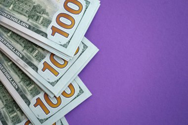 Mor arka planda büyük miktarda yüz dolarlık banknotlar. ABD 'de vergilendirme ve para yapma kavramı