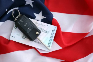 Uzaktan kumandalı ateşleme anahtarları ve ABD bayrağında ehliyet kartı. Amerika 'da araba kullanma kavramı. Araç sahipliği
