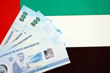 Birleşik Arap Emirlikleri kara para birimi banknotları bayrağa yakın duruyor. İş ve yatırım kavramı