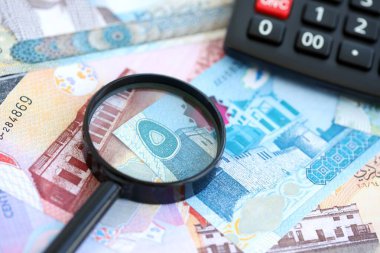 Bahreyn dinar para birimi faturaları ve yakınlaştırıcı bardaklı hesap makinesi. Vergilendirme ve para sayımı kavramı