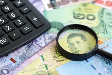 Tayland baht para birimi faturaları ve yakınlaştırıcı bardaklı hesap makinesi. Vergilendirme ve para sayımı kavramı