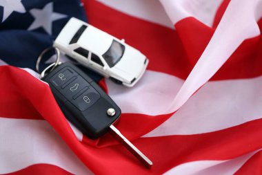 Uzaktan kumandalı ateşleme anahtarları ve Amerikan bayrağında oyuncak araba. Amerika 'da araba kullanma kavramı. Araç sahipliği