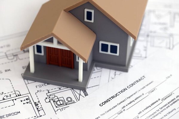 КИЕВ, УКРАИНА - 3 ОКТЯБРЯ 2025 г. Контракт на строительство и игрушечный домик на белых чертежах для строительства вблизи