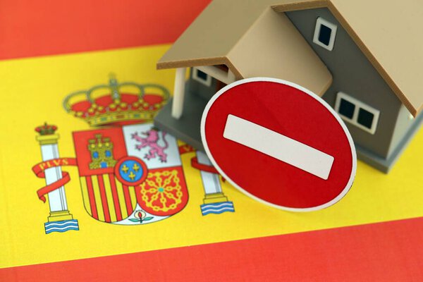 Residential house with stop sign on Spanish flag close up. Concept of Squatting in Spain. Okupas problem