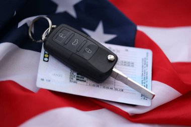 Uzaktan kumandalı ateşleme anahtarları ve ABD bayrağında ehliyet kartı. Amerika 'da araba kullanma kavramı. Araç sahipliği