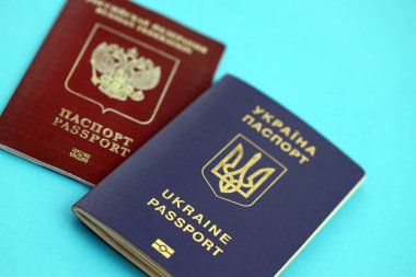 Açık mavi masa arkaplanındaki Ukrayna ve Rusya Federasyonu pasaportları yakın plan. Ukrayna 'daki savaş sırasında kısıtlamalar ve yaptırımlar kavramı