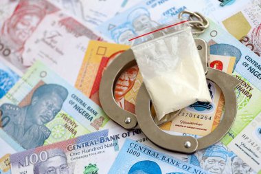 Nijerya naira para birimi faturaları ve kelepçeli kokain paketi. Uyuşturucu suçları kavramı