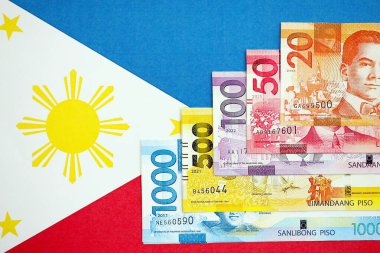 Filipinler Peso para birimi banknotları bayrağın üzerinde duruyor. İş ve yatırım kavramı