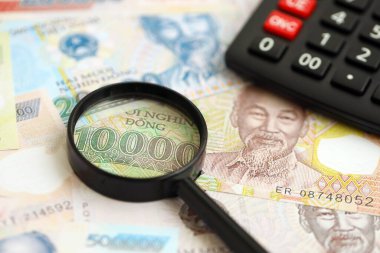 Vietnam dong para birimi faturaları ve büyüteçle yakınlaştırılmış hesap makinesi. Vergilendirme ve para sayımı kavramı