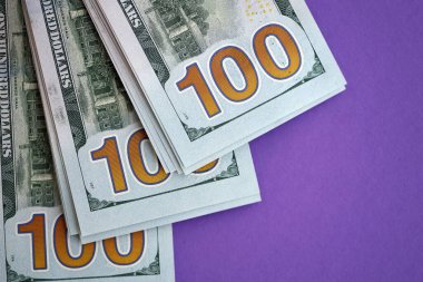 Mor arka planda büyük miktarda yüz dolarlık banknotlar. ABD 'de vergilendirme ve para yapma kavramı