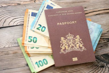 Hollanda pasaportu, ahşap arka planda Avro para banknotlarıyla kaplıdır. Avrupa konseptinde nakit ve ödemeler