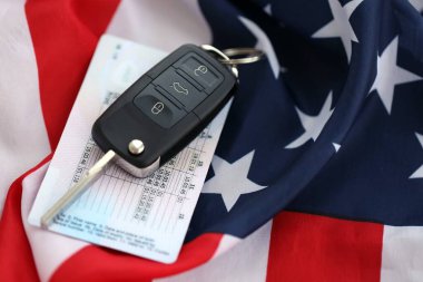Uzaktan kumandalı ateşleme anahtarları ve ABD bayrağında ehliyet kartı. Amerika 'da araba kullanma kavramı. Araç sahipliği