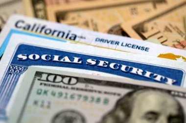 Social security number and California driving license with US dollar money bills close up