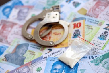 Nijerya naira para birimi faturaları ve kelepçeli kokain paketi. Uyuşturucu suçları kavramı