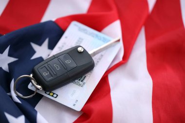 Uzaktan kumandalı ateşleme anahtarları ve ABD bayrağında ehliyet kartı. Amerika 'da araba kullanma kavramı. Araç sahipliği