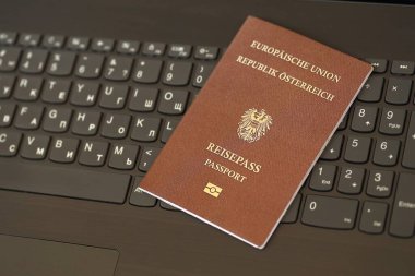 Avusturya pasaportu siyah dizüstü bilgisayarın klavye tuşlarının üzerinde duruyor. Avrupa konseptinde teknoloji ve kontrol