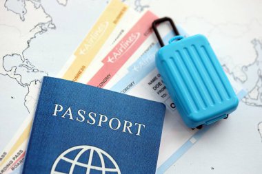 Passport with boarding pass tickets and toy luggage bag on world map close up