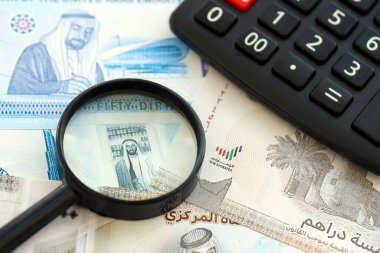 Birleşik Arap Emirlikleri kara para birimi faturaları ve büyüteçle yakınlaştırılmış hesap makinesi. Vergilendirme ve para sayımı kavramı