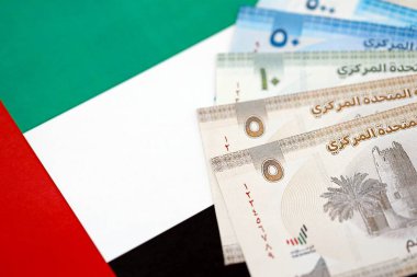Birleşik Arap Emirlikleri kara para birimi banknotları bayrağa yakın duruyor. İş ve yatırım kavramı