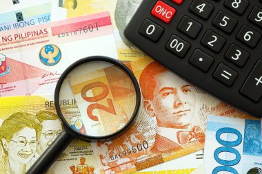 Filipinler Peso para birimi faturaları ve yakınlaştırıcı bardaklı hesap makinesi. Vergilendirme ve para sayımı kavramı