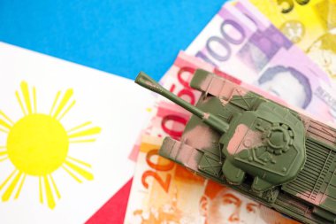 Filipinler 'in para birimi faturaları ve oyuncak tankları bayrakta. Ordu fonları ve silah satışları kavramı