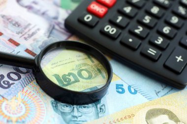 Tayland baht para birimi faturaları ve yakınlaştırıcı bardaklı hesap makinesi. Vergilendirme ve para sayımı kavramı