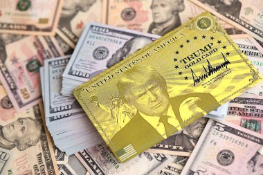 KYIV, UKRAINE - 13 ARALIK 2025 Trump altın kart hatırası büyük miktarda Amerikan doları banknotları yakın çekim