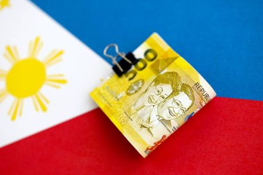 Filipinler Peso para birimi banknotları bayrağın üzerinde duruyor. İş ve yatırım kavramı