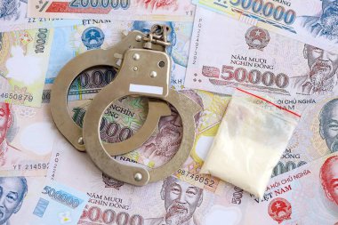 Vietnam dong para birimi faturaları ve kelepçeli kokain paketi. Uyuşturucu suçları kavramı