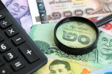 Tayland baht para birimi faturaları ve yakınlaştırıcı bardaklı hesap makinesi. Vergilendirme ve para sayımı kavramı