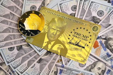 KYIV, UKRAINE - 13 Aralık 2025 Trump altın kartı ve hatıra parası büyük miktardaki 100 dolarlık banknotlar
