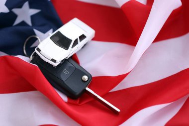 Uzaktan kumandalı ateşleme anahtarları ve Amerikan bayrağında oyuncak araba. Amerika 'da araba kullanma kavramı. Araç sahipliği