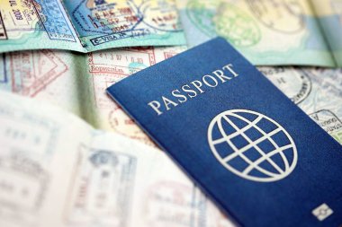 Birçok açık pasaport sayfası, bir sürü vize ve çeşitli ülkelerden pasaport kontrolünden giriş damgalarıyla dolu. Dünya çapında seyahat ve turizm kavramı