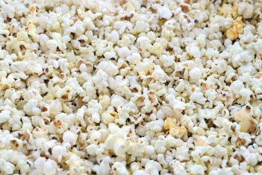 Büyük bir grup taze pişmiş patlamış mısır, sıcak sarı ışıkta yumuşak bir odak ile fotoğraflanmış, bir sokak gıda pazarında satışa sunuldu.