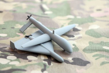 Gri oyuncak İHA modelleri kamuflaj kumaşında yakın plan. Kamikaze insansız hava aracı ve gözlem aracı