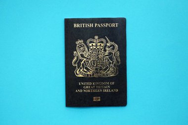 British passport book on light blue paper background close up. Travel document on blue surface